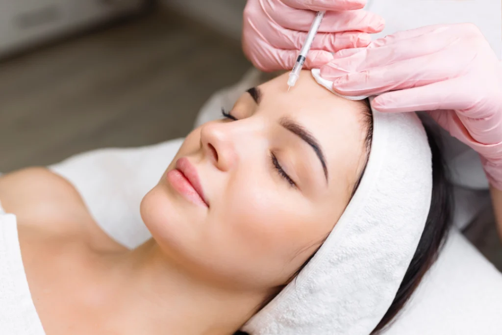 A patient receives a Botox injection on her forehead during a professional treatment session.