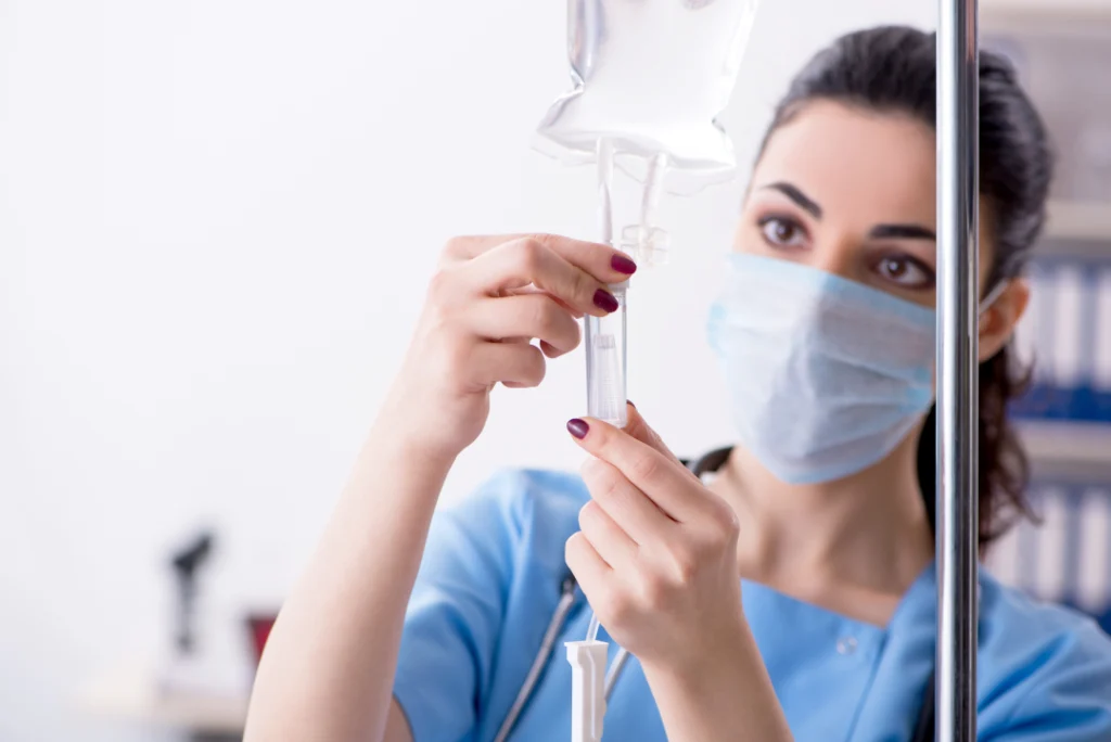 A healthcare professional preparing an IV drip for patient treatment.