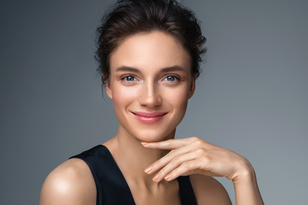A youthful woman smiling with radiant skin after injectables.