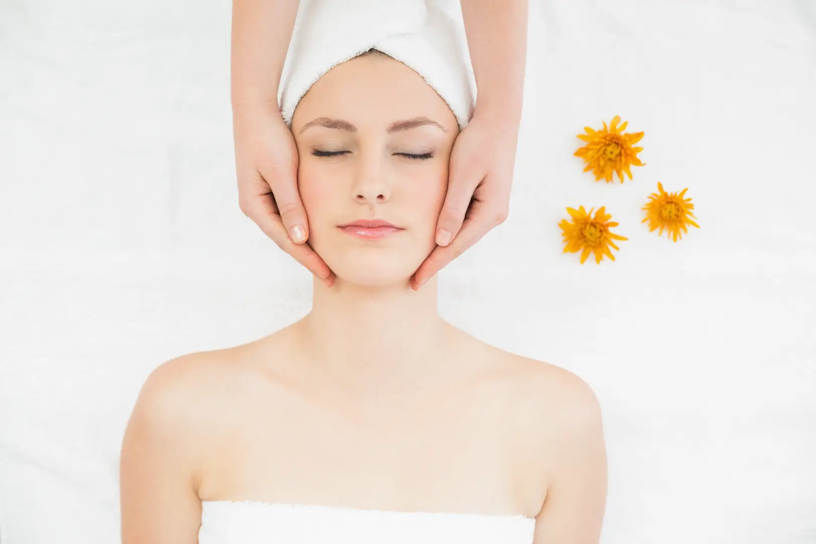 Woman receiving a facial massage while lying on a spa treatment bed.